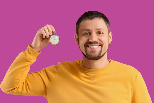 Young man with stopwatch on violet background