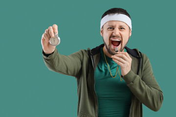 Male trainer with whistle and stopwatch on green background