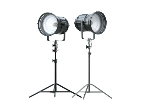 Two studio lights stand ready on tripod legs against black