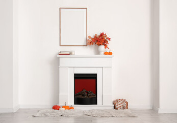 Fototapeta premium Fireplace, pumpkins and vase with beautiful autumn leaves in interior of living room