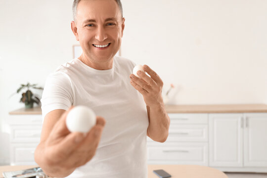 Mature man with boiled eggs in kitchen