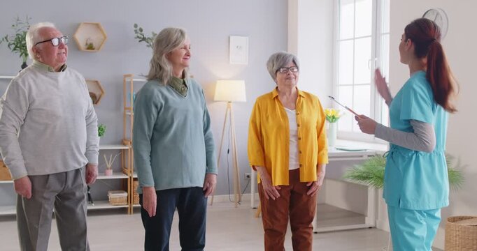 Friendly doctor interacting with senior patients in a nursing home, giving high fives during a meeting. Talking, promoting care, support, and engagement to enhance emotional well-being.
