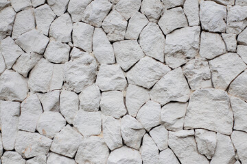 Close-up of a natural stone wall featuring irregularly shaped white stones. Ideal for backgrounds, textures, or design inspiration.