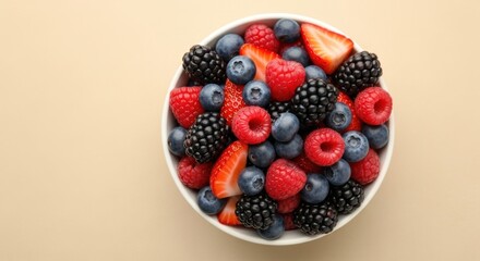 Healthy fruit salad in white bowl with fresh strawberries blackberries and raspberries on beige