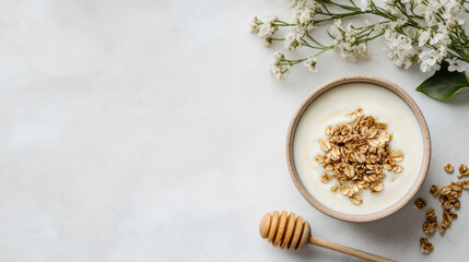 Fototapeta premium Creamy yogurt bowl with granola and honey dipper, gentle sunlit flatlay