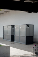Modern outdoor designated smoking area booths with glass walls and cigarette icons under a roof.