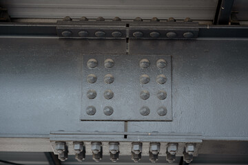 Close-up detail of heavy black steel beam construction with bolted joints and industrial rivets.