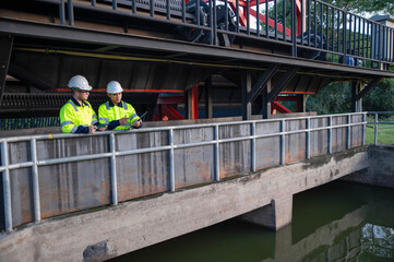 Naklejka premium A professional engineer and an inspector are jointly seriously inspecting the water filtration of a water filter inside a treatment pond.