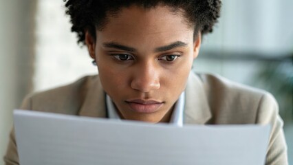 Focused woman examining documents with an intent expression in a professional setting.