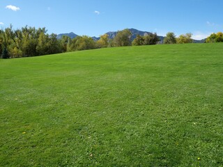 Fototapeta premium Green Lawn Hill and the Flatirons beneath a Clear Blue Autumn Sky, Boulder, Colorado