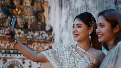 Young thai friends celebrating loi krathong day taking selfie at wat arun