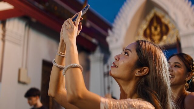 Woman capturing temple architecture and cultural event with smartphone at night