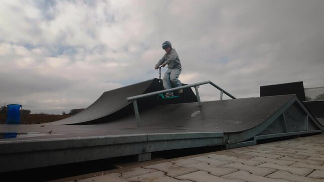Young scooter skater practices ramp jump trick technique Slow-mo action