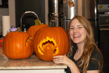 joyful woman with carved pumpkin, happy lady posing beside intricately carved pumpkin in kitchen setting