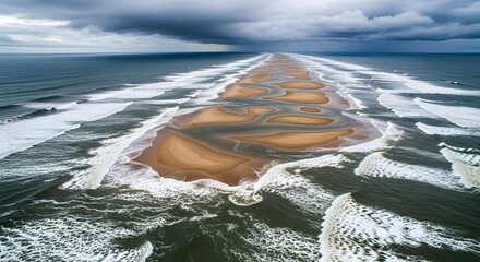 Aerial view of sandy beach spits with tidal pools and breaking ocean waves under a cloudy sky