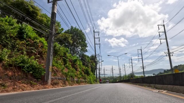 Motorcyclist Rides Along Sunny Phuket Urban Roadway