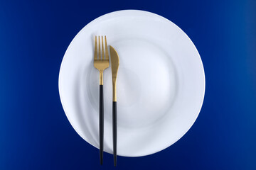 Elegant Table Setting with Gold Cutlery on a Blue Background