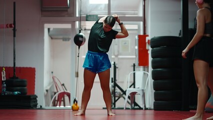 Female athlete stretching at a gym, preparing for muay thai shadow boxing session