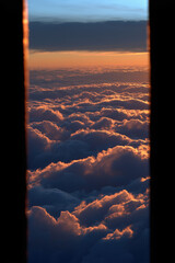 Rim-lit towering cloud pillars on either side of a glowing horizon with dark negative space for text