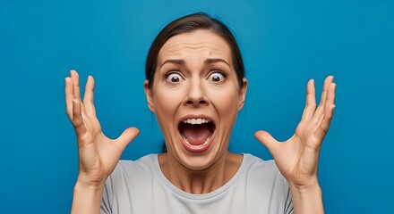 Woman screaming with hands raised in the air against a vibrant blue background expressing intense emotion