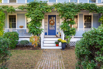 Charming front entry of a vine-covered family house with blue door and fall decorations in Boston,...