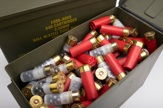 Pile of 12 gauge bullet shotgun shell in green army ammo crate on white background