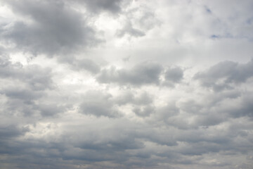 Dense grey clouds blanket sky, creating an expansive overcast atmosphere. Beautiful pensive weather patterns show dark and white tones blending dramatic, gloomy formation. Cloudy environment feels