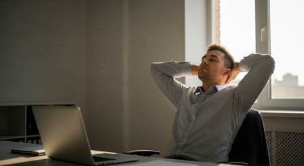 Young caucasian male relaxing in office chair near sunlit window