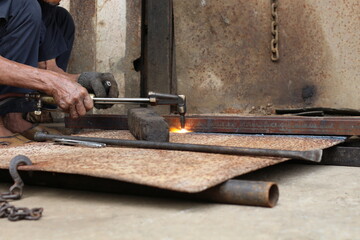 Metalworker using a torch to cut through a piece of metal in a workshop