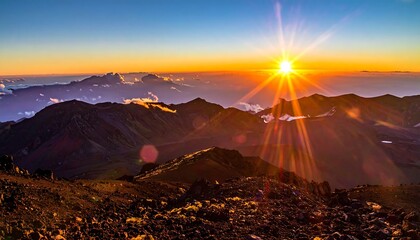 A vibrant sunrise casts golden rays over a rugged, mountainous landscape with layers of peaks and clouds, creating a scenic vista