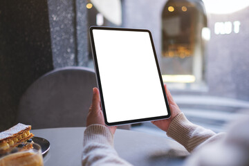 Mockup image of a woman holding digital tablet with blank white desktop screen in cafe