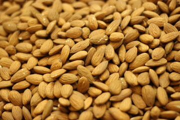 Raw almond nuts texture background showing whole shelled almonds pile and natural brown skin