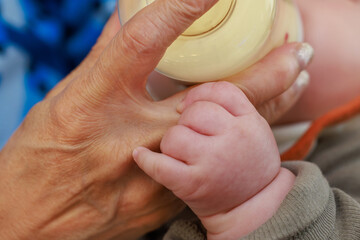 哺乳瓶からミルクを飲む赤ちゃんの手