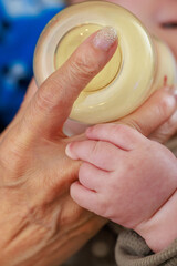 哺乳瓶からミルクを飲む赤ちゃんの手