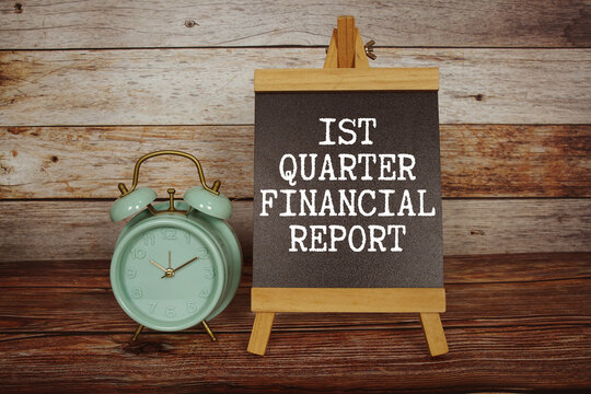 1st Quarter Financial Report text on easel blackboard with alarm clock on wooden background