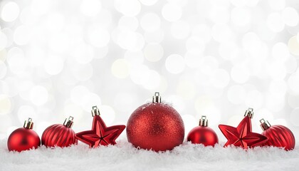 Festive red ornaments on snow sparkle against a bokeh background to evoke joy and holiday cheer.