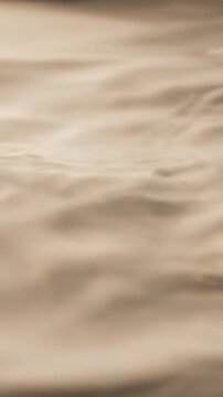 Abstract blank surface of a thick milky liquid reflects shifting subsurface light waves moving slowly creating a subtle texture pattern moving slowly, milky white, water