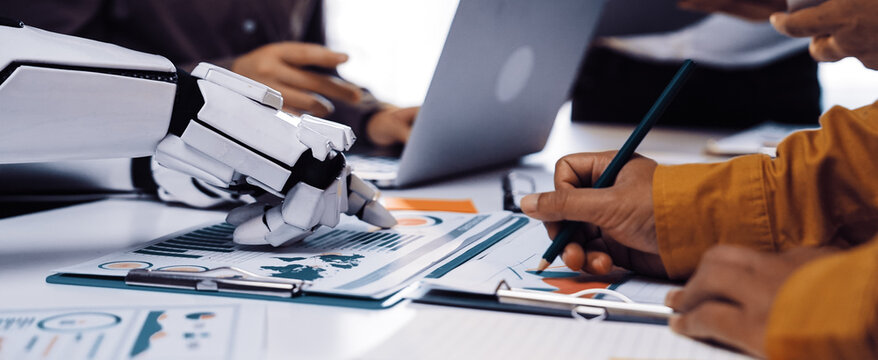 A modern office scene featuring a robotic arm assisting in a business meeting, highlighting collaboration, data analysis, and the integration of technology in professional settings.Noogenesis - Powered by Adobe