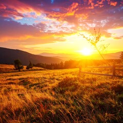 Fototapeta premium A vibrant sunset paints the sky with fiery hues. Gently rolling hills lead to distant mountains, illuminated. A wooden fence rests on golden grass