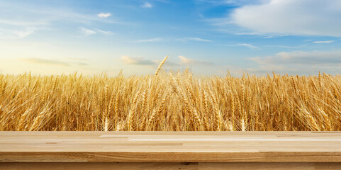 Golden Wheat Field: A picturesque panorama of a golden wheat field basks under a bright blue sky, with a rustic wooden table in the foreground, creating a harmonious blend of nature and utility.