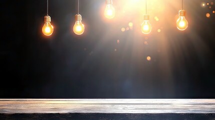 Five glowing incandescent light bulbs hang from above, illuminating a dark background with rays of warm light and a wooden surface in the foreground.