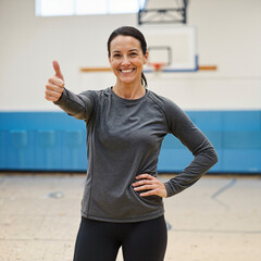 Gym teacher giving a thumbs up with a big smile in basketball court  