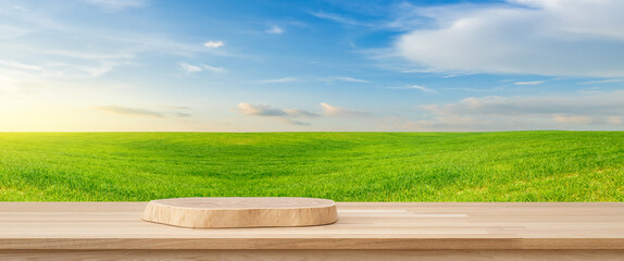 Product Placement: A natural wood pedestal stage takes center stage amidst a vast, vibrant green field and an expansive blue sky. Ideal for showcasing a product or message.