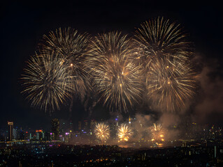 Golden fireworks burst over a cityscape at night, illuminating the dark sky