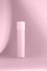 A vertical shot of a minimalist, cylindrical frosted bottle on a light pink background with soft shadows, creating an elegant and clean feel.