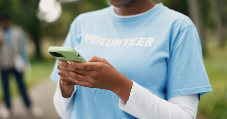 Hands, phone and volunteer with woman outdoor for charity, community outreach or food drive. App, text message and typing with person in park for activism, ngo donation or non profit communication