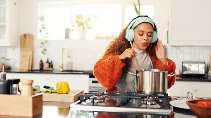 Cooking, music and pot with woman in kitchen of home for flavor, food or meal preparation. Cuisine, headphones and streaming with person stirring at counter in apartment for diet, health or nutrition © FlexOn/peopleimages.com