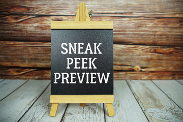 wooden easel holds a blackboard with the white text "Sneak Peek Preview" set against a rustic wooden wall and light-colored wooden floor