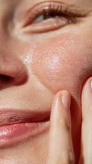 Fototapeta premium Close-up of a woman smiling while touching her radiant skin, showcasing a healthy skincare routine and natural beauty.