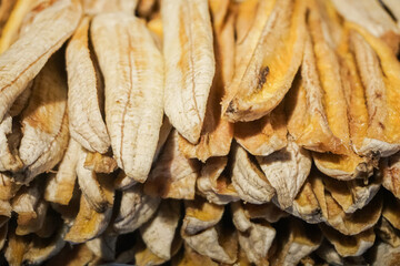 sun-dried or dehydrated banana slices (Kluay Tak). The concept focuses on the mass production and organic texture of the food product. The image highlights the variations in color—ranging from white